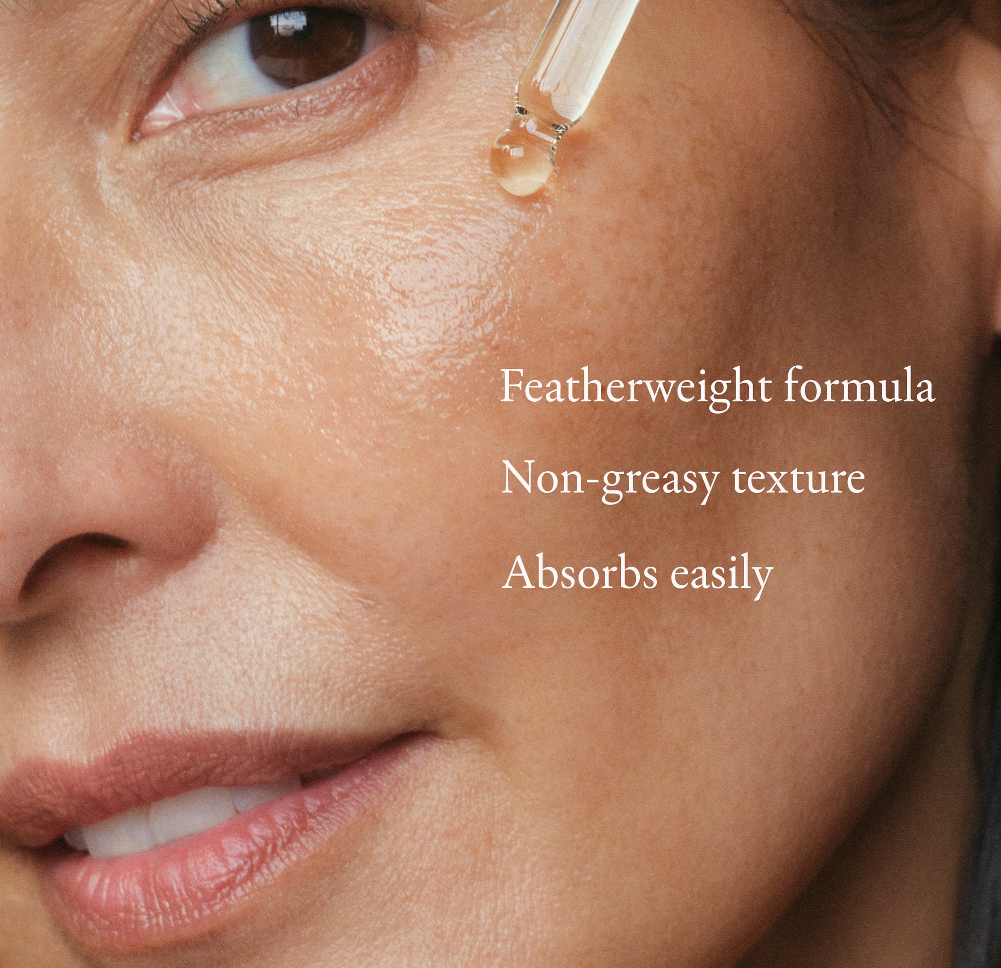 Woman holding a dropper of face oil on her cheek