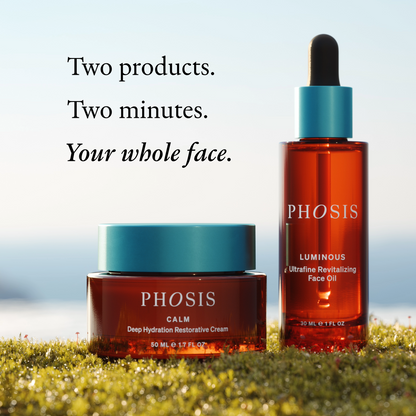 Two PHOSIS skincare products displayed outdoors on grass against a soft sky background: a jar of PHOSIS CALM deep hydration restorative cream and a bottle of PHOSIS LUMINOUS ultrafine revitalizing face oil.